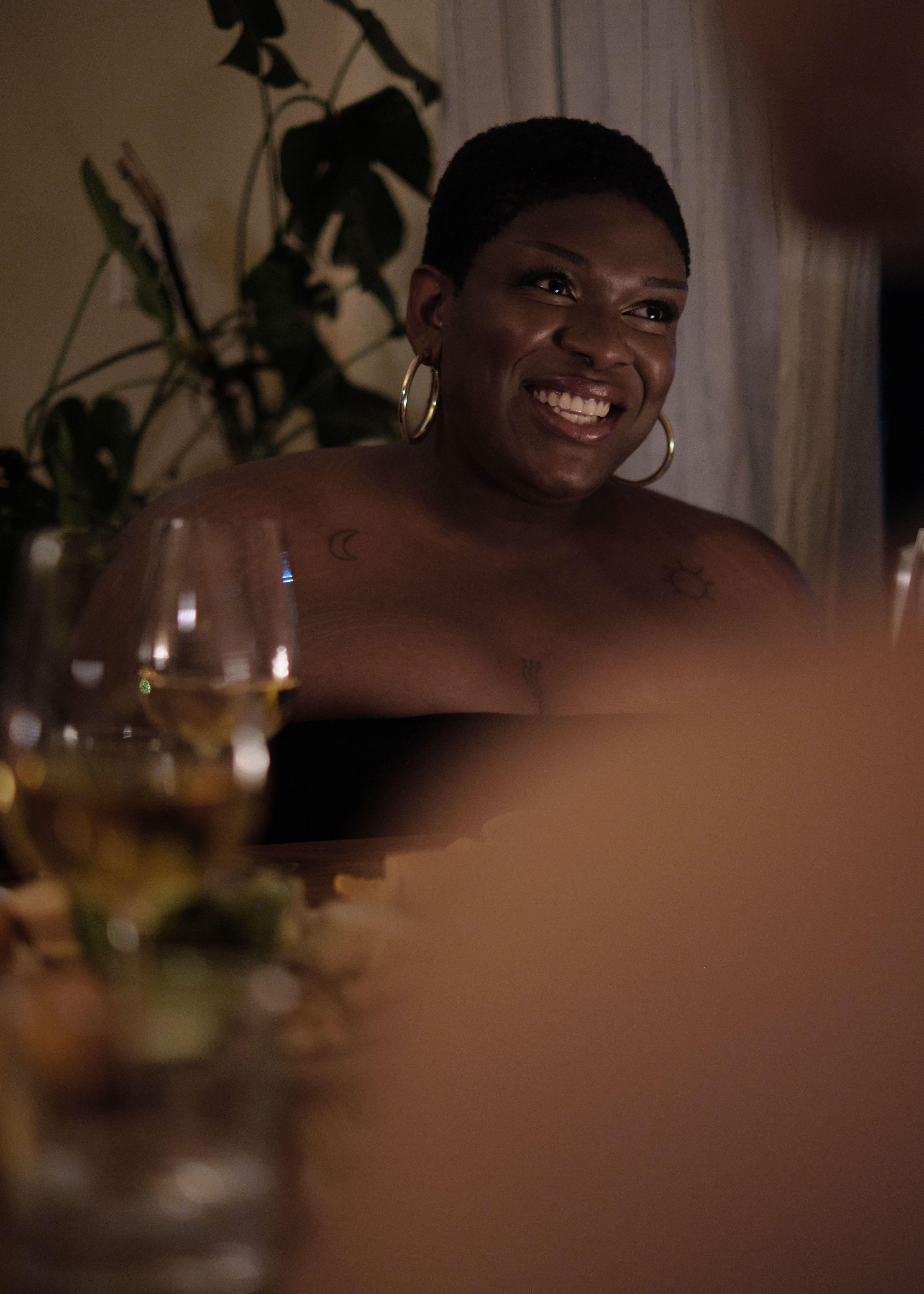 A non-binary trans woman smiling at a dinner party